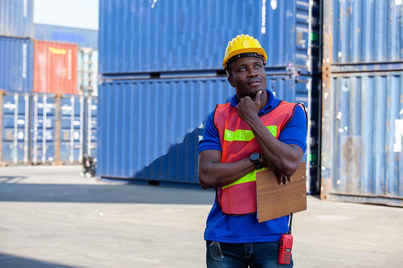 Portrait of happy man at cargo container. Young worker man with doc in the construction container yard
